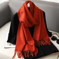 Close-up of soft rust red scarf with tassel edge draped over a black outfit - Dark Orange