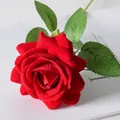 Single red velvet artificial rose with green leaves on white magazine background - Red