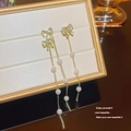 Close-up of elegant gold long tassel earrings with pearls and bowknot on jewelry box - Gold Bowknot Pearl Tassel