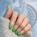 Close-up of glossy gradient press-on nails from nude to green in a long coffin shape - Nude Green Gradient