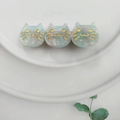 Close-up of cute light blue marble pattern cat hair clip with gold facial details - Iridescent Cyan