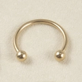 Golden 16G stainless steel horseshoe piercing ring with polished balls on fabric background - 1.2x8x3mm / Gold