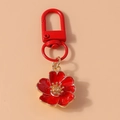 Détail d'un porte-clés à fleurs rouges avec bords dorés et fermoir en métal rotatif - Rouge