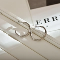 Detailed macro view of silver wavy hoop earrings with irregular flowing design texture - Silver Hoop
