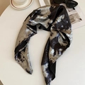 Close-up of Y2K liquid silver scarf with leopard print texture on a marble tabletop - Black Silver