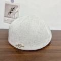 Dettaglio di un basco in maglia grigio chiaro con paillettes e un nodo a forma di cuore - Bianco