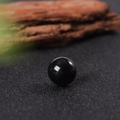 Polished black obsidian natural gemstone sphere on a textured dark background - Obsidian