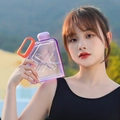 Flat purple gradient square sports water bottle with orange handle held by a woman - Purple