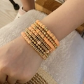 Detailed view of layered bohemian bracelets with peach clay discs and gold metallic beads - Orange