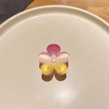 Macro detail of the gradient pink acrylic plumeria hair claw clip on a wooden desk - Colorful Plumeria Pink Yellow