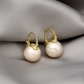Macro shot of elegant light pink pearl earrings with gold hooks on gray silk fabric - Champagne