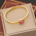 Retro gold stainless steel bangle featuring a pink oval opal stone on a vintage book - Bracelet / Gold with Pink Cat Eye Stone
