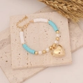 Dettaglio del bracciale bohémien con ciondolo a cuore dorato e perle bianche - Blu (6#)