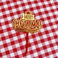 Macro shot of red and gold acrylic Merry Christmas cake topper on red plaid fabric - Red Gold Double Layer Merry Christmas