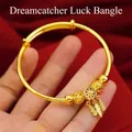 Adjustable golden dreamcatcher bangle with feather charms on a velvet backdrop - Gold