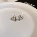 Macro shot of silver heart-shaped stud earrings with wire-wrap design on a white ceramic tray - 55# Silver Heart