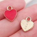Red enamel and gold heart charm pendants held on finger showing delicate jewelry size - Big Red Heart (11027)