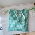 Flat lay di borsa tote in tela vichy verde floreale con libro e fermacapelli - Floreale a Griglia Verde Scuro