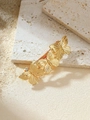 Detailed view of three golden metal butterflies on a hair clip over a textured stone base - Gold Butterfly