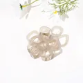 Close-up of minimalist translucent flower hair claw clip with golden metal spring - Hollow Five-Petal Flower - Jelly Grey