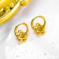 Detailed close-up of golden 3D flower earrings on white natural stone base - Earrings / Gold