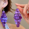 Détail de boucles d'oreilles pendantes en nacre violette sur un modèle pour les vacances - Violet