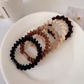 Five-pack of elastic spiral hair ties in earth-toned colors on a minimalist white plate - Spiral Mixed 5pcs (Bagged)
