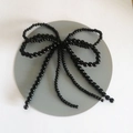 Dettaglio di un elegante fiocco di perline nere con nappe per decorare le scarpe - Doppio Fiocco Nero