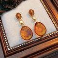 Close-up of amber resin water drop earrings on vintage frame and linen texture background - Water Drop Long Dangle Earrings / Golden Coffee