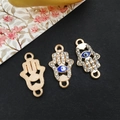 Detailed macro of golden Hamsa Hand charms with blue Evil Eye and sparkling rhinestones - KC Gold - Hamsa Hand Connector - 12x21mm