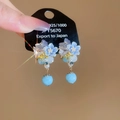 Detalle de pendientes de flor azul claro con agujas de plata 925 y perlas con lazos - Perno de plata-Azul