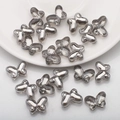 Close-up of 10x14mm silver butterfly glass beads scattered on a white ceramic plate - Smoke Gray