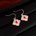 Macro view of gold flower earrings with red gemstone and sparkling clover details - Red Zircon Geometric Ear Hook