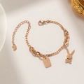 Elegantes roségoldenes Titanarmband mit Hasenanhänger und graviertem Anhänger auf Beige - Roségold