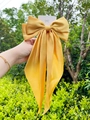 Detail of yellow satin oversized bow hair clip with elegant long ribbons on cardboard - Scarf Bow / Mango Yellow