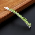 Close-up of small silver hair clip with natural green crystal stones on a wood tray - Peridot with Silver Clip