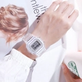 Transparent digital sports watch with LED display worn on wrist in a lifestyle setting - White