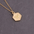Close-up of golden necklace featuring a hexagonal shield pendant with embossed letter W - Letter W (23#W)