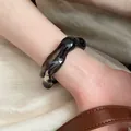 Close-up of translucent dark grey acrylic bangle with irregular wave texture on model - Wave Irregular Bangle / Black
