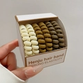 Set mit 4 braunen matten Spiral-Haargummis in Box, gehalten von einer gepflegten Hand - 11# Kaffee Serie