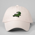 Close-up of green cartoon crocodile embroidery on a light pink cotton baseball cap - Beige