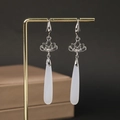 Detail of silver lotus earrings with white chalcedony waterdrop pendants on a gold stand - Waterdrop Lotus H2875