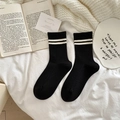 Cozy black ribbed wool socks with white stripes on white bed sheets in a lifestyle setting - One Size / Black with White Double Stripes Cuff