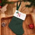 Green knitted Christmas stocking with red letter N embroidery and pine cone decorations - Letter N