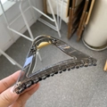 Detail of large triangular hair claw clip in smoky gray acrylic with gold spring - Transparent Black