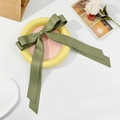 Detailed view of an olive green satin double-layer bow hair clip on a pink ceramic plate - Dark Green