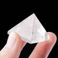 Clear natural crystal pyramid with ice crack texture held between fingers - 2.5cm