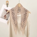 Detail of beige paisley silk scarf texture on a wooden hanger with white satin top - Beige