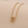 Macro detail of golden necklace with sparkling letter S pendant inlaid with zircon crystals - Letter S