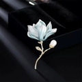 Elegant magnolia flower brooch with light blue enamel petals and a white pearl on gold base - Magnolia Blue